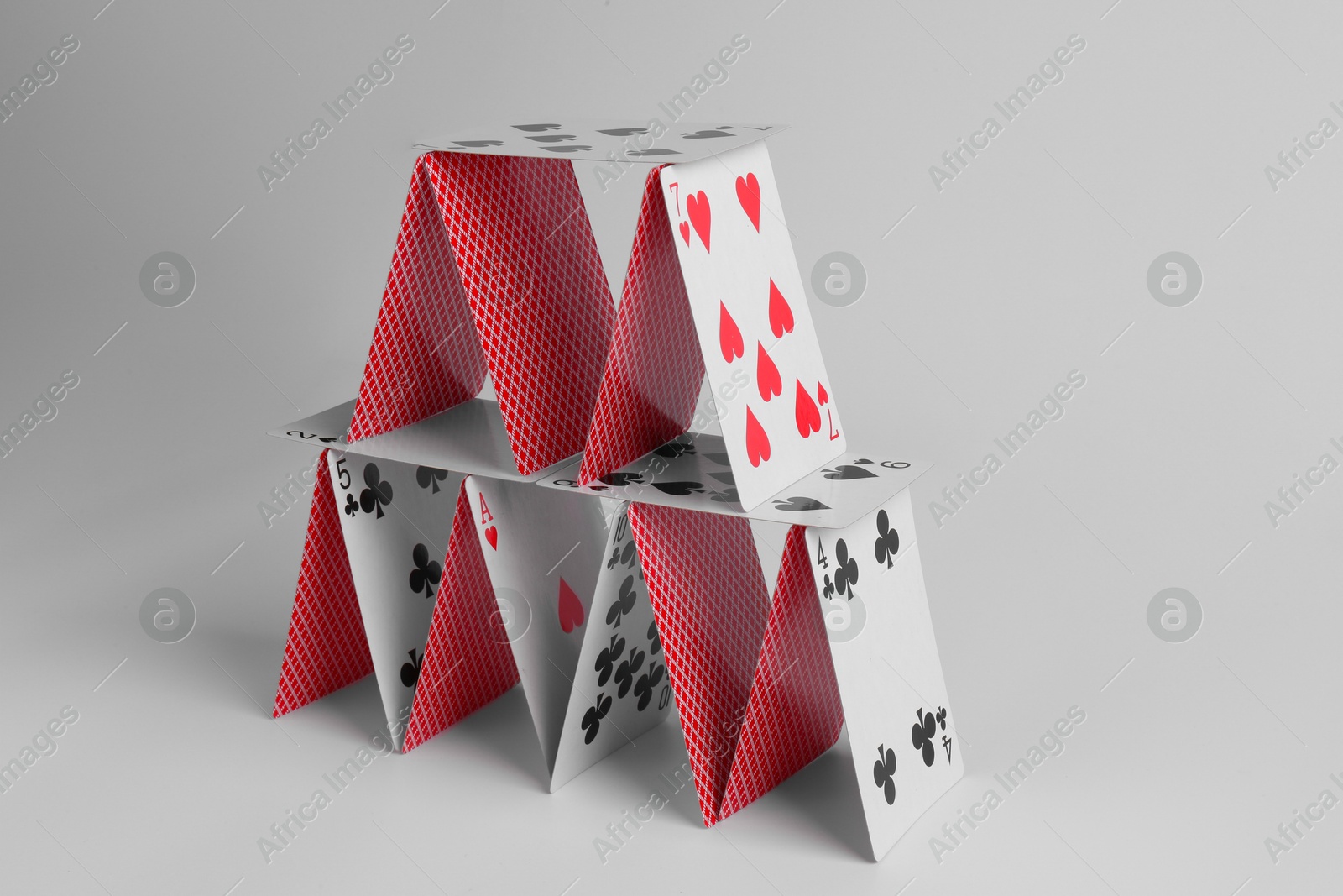 Photo of House of playing cards on light grey background