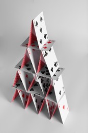 Photo of House of playing cards on light grey background