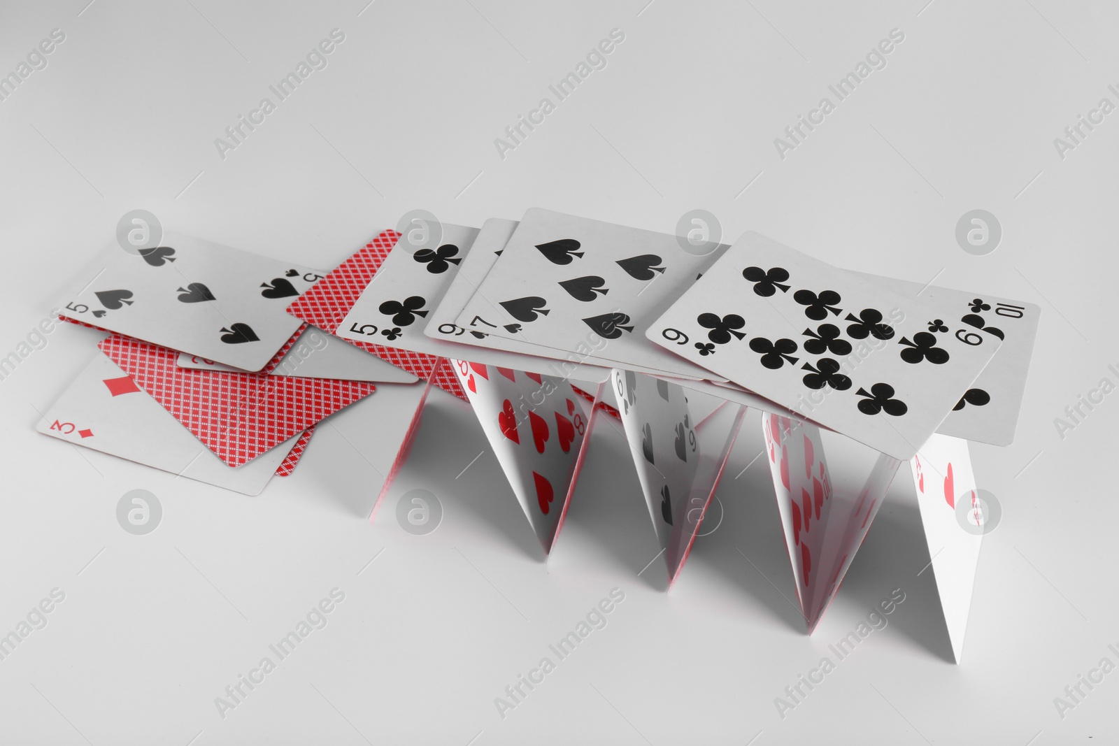 Photo of Collapsed house of playing cards on light grey background