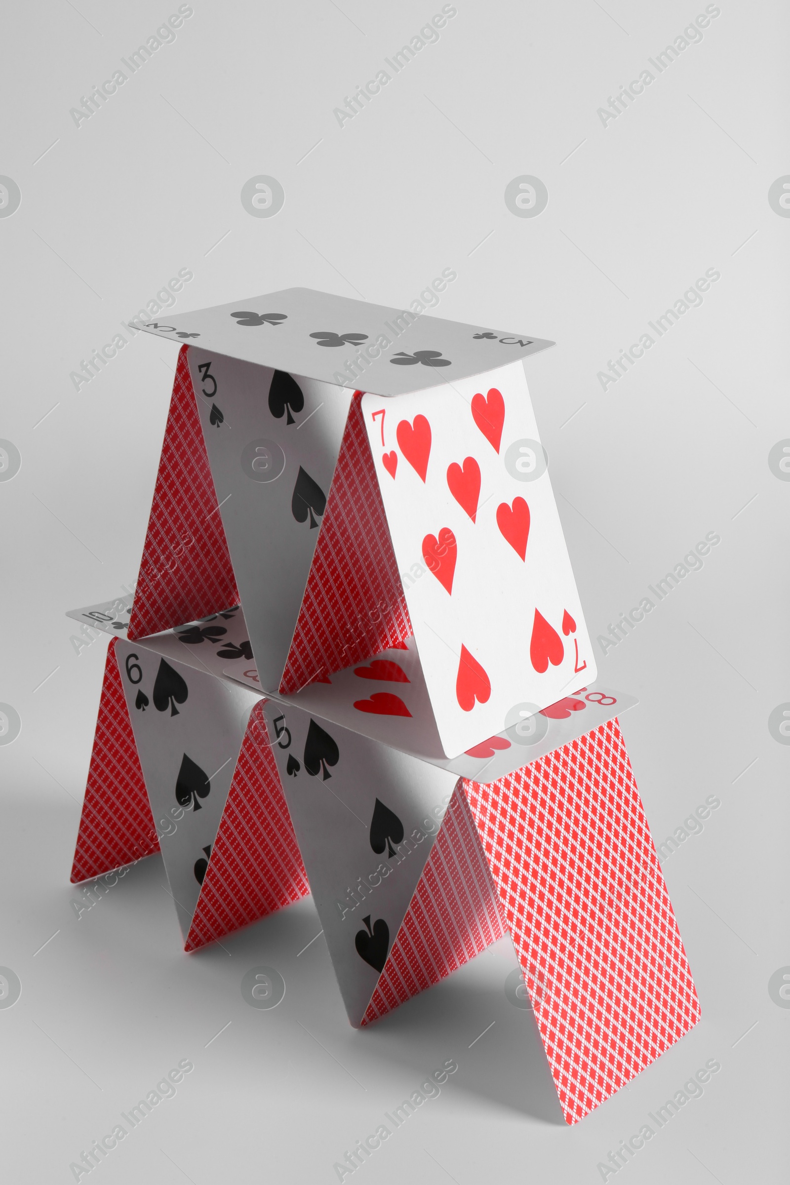 Photo of House of playing cards on light grey background