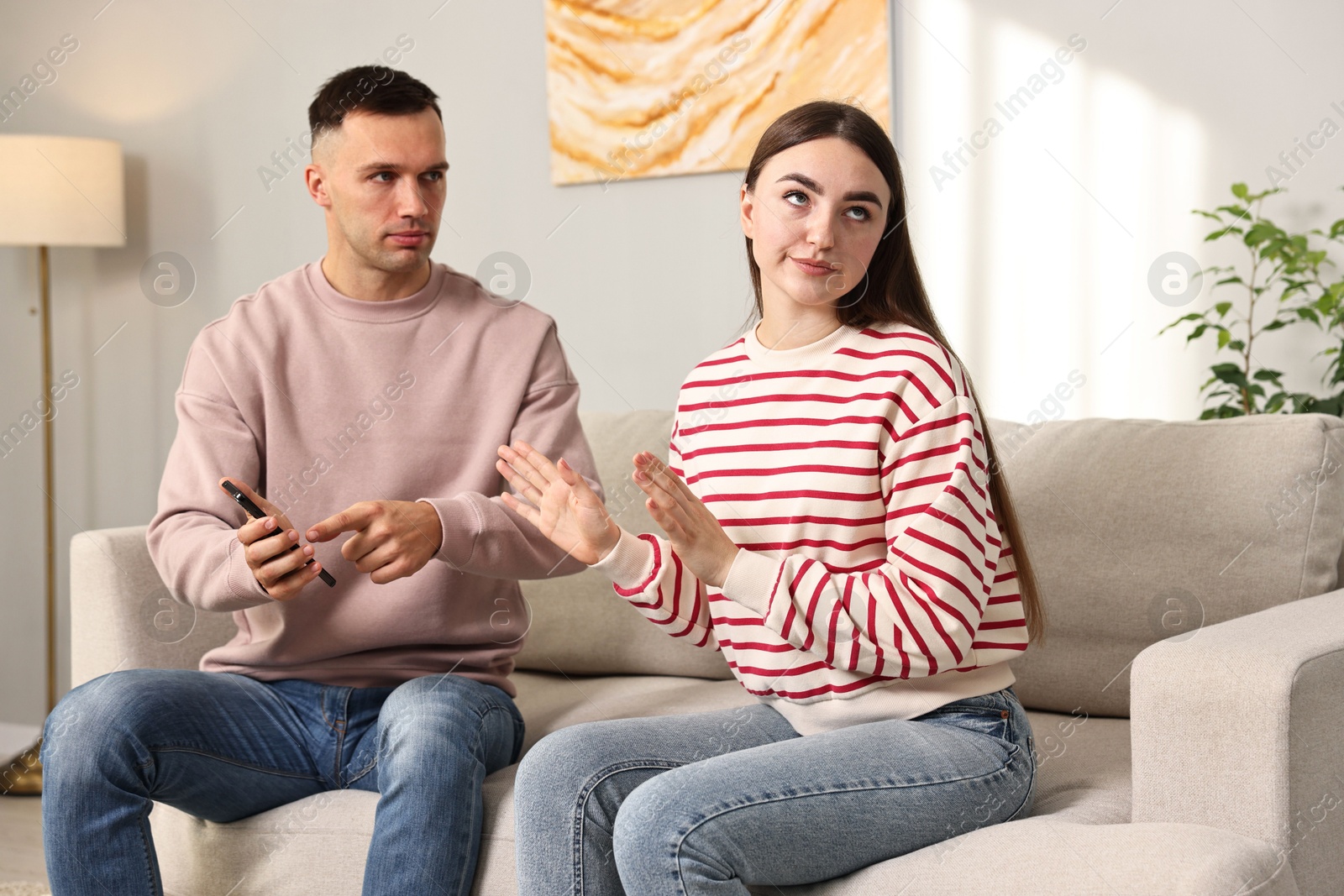 Photo of Husband showing smartphone with proofs to his unfaithful wife at home