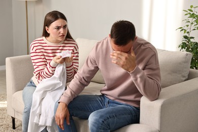 Wife showing shirt with lipstick marks as proof to her unfaithful husband at home