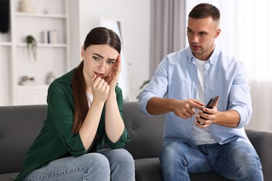 Photo of Husband showing smartphone with proofs to his unfaithful wife at home