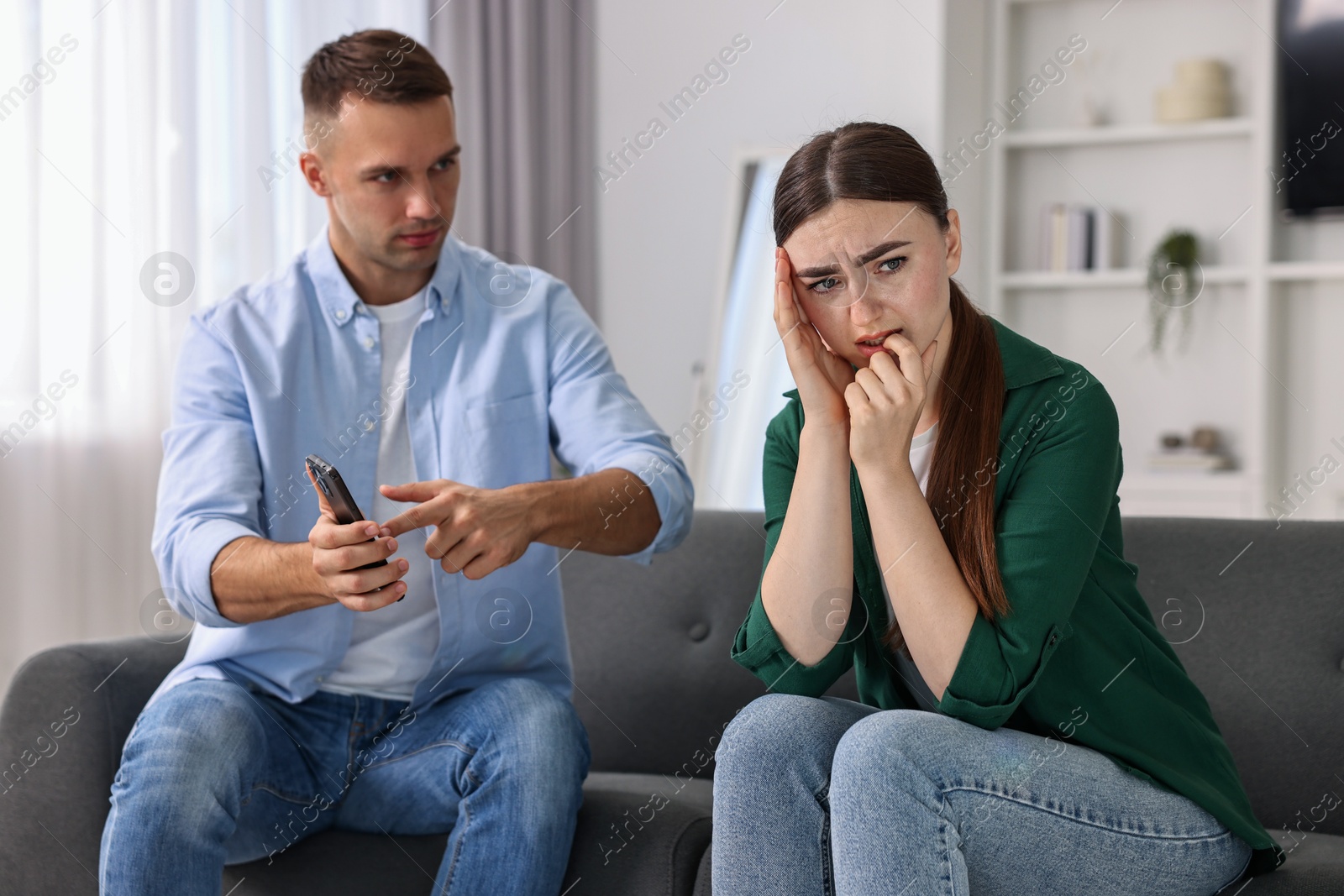 Photo of Husband showing smartphone with proofs to his unfaithful wife at home