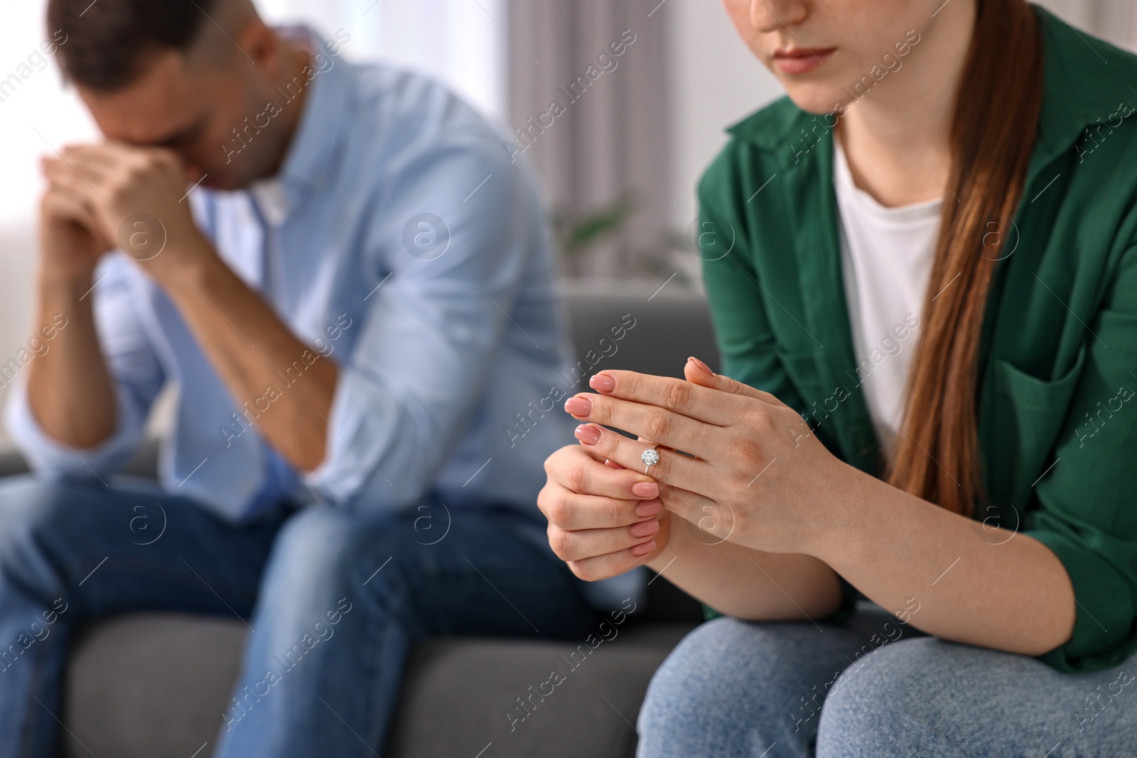 Photo of Woman taking off engagement ring after quarrel with her husband at home, closeup