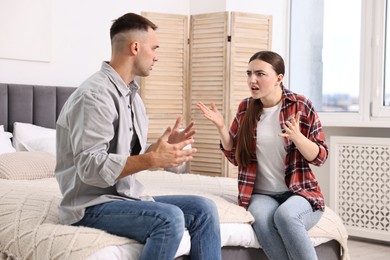 Photo of Young couple arguing on bed at home