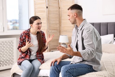 Photo of Young couple arguing on bed at home