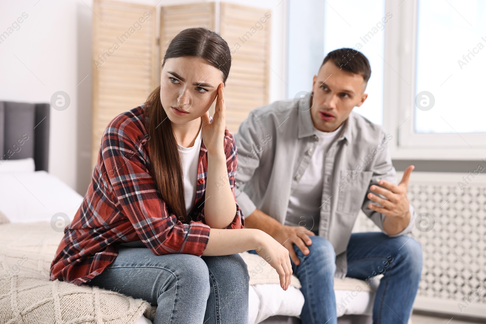 Photo of Upset woman ignoring her husband at home, selective focus