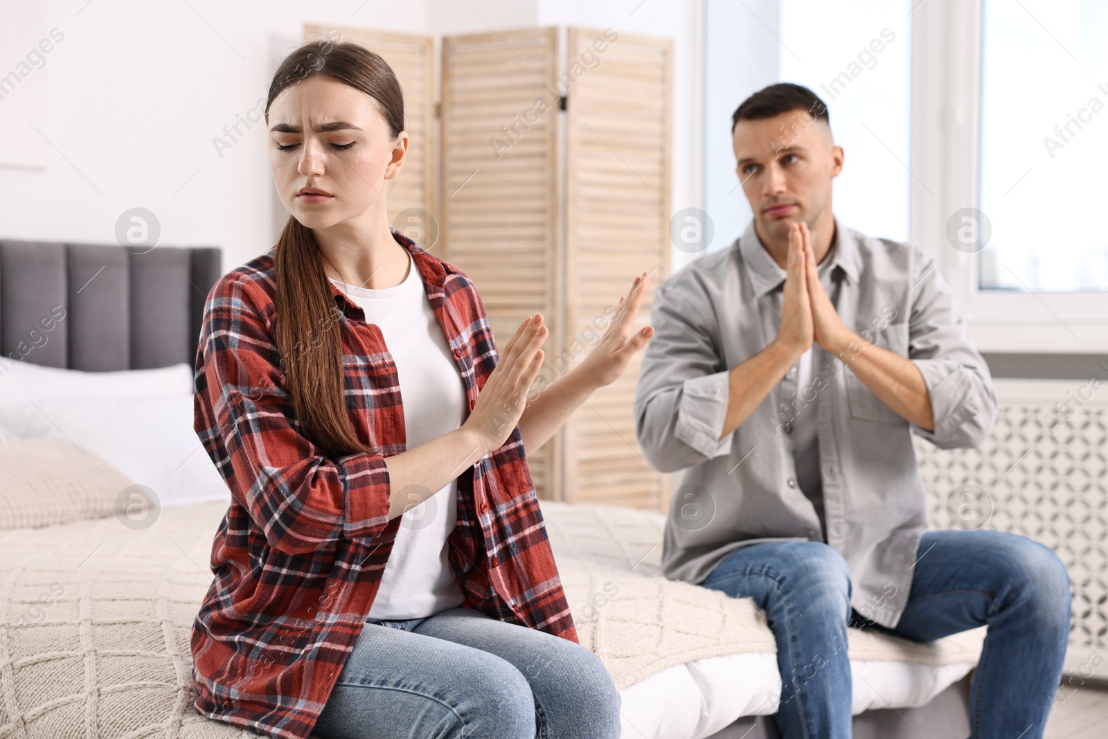 Photo of Husband apologizing his wife while she stopping him at home, selective focus