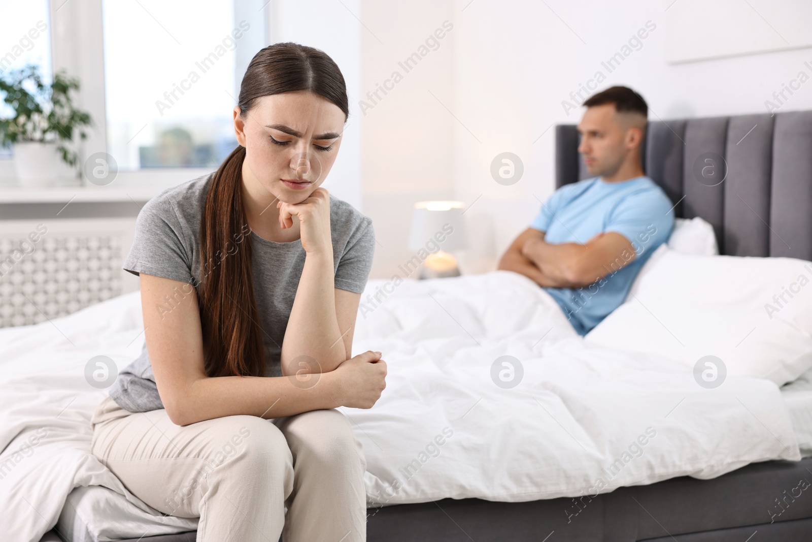 Photo of Offended couple ignoring each other in bedroom, selective focus