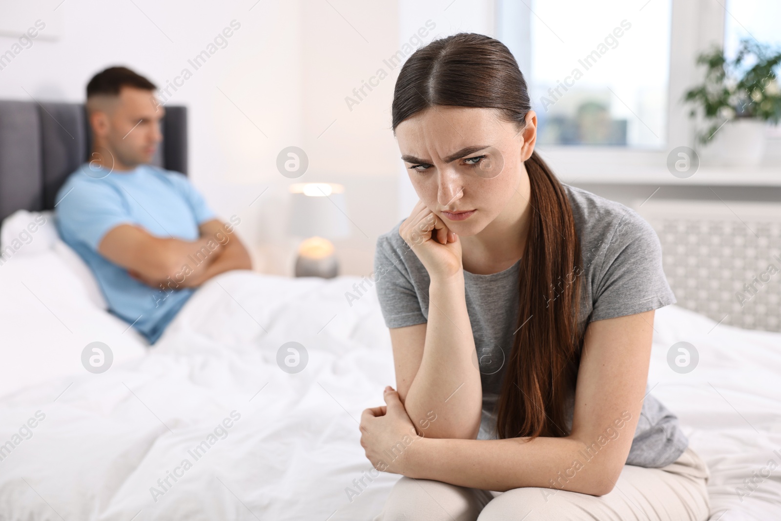 Photo of Offended couple ignoring each other in bedroom, selective focus