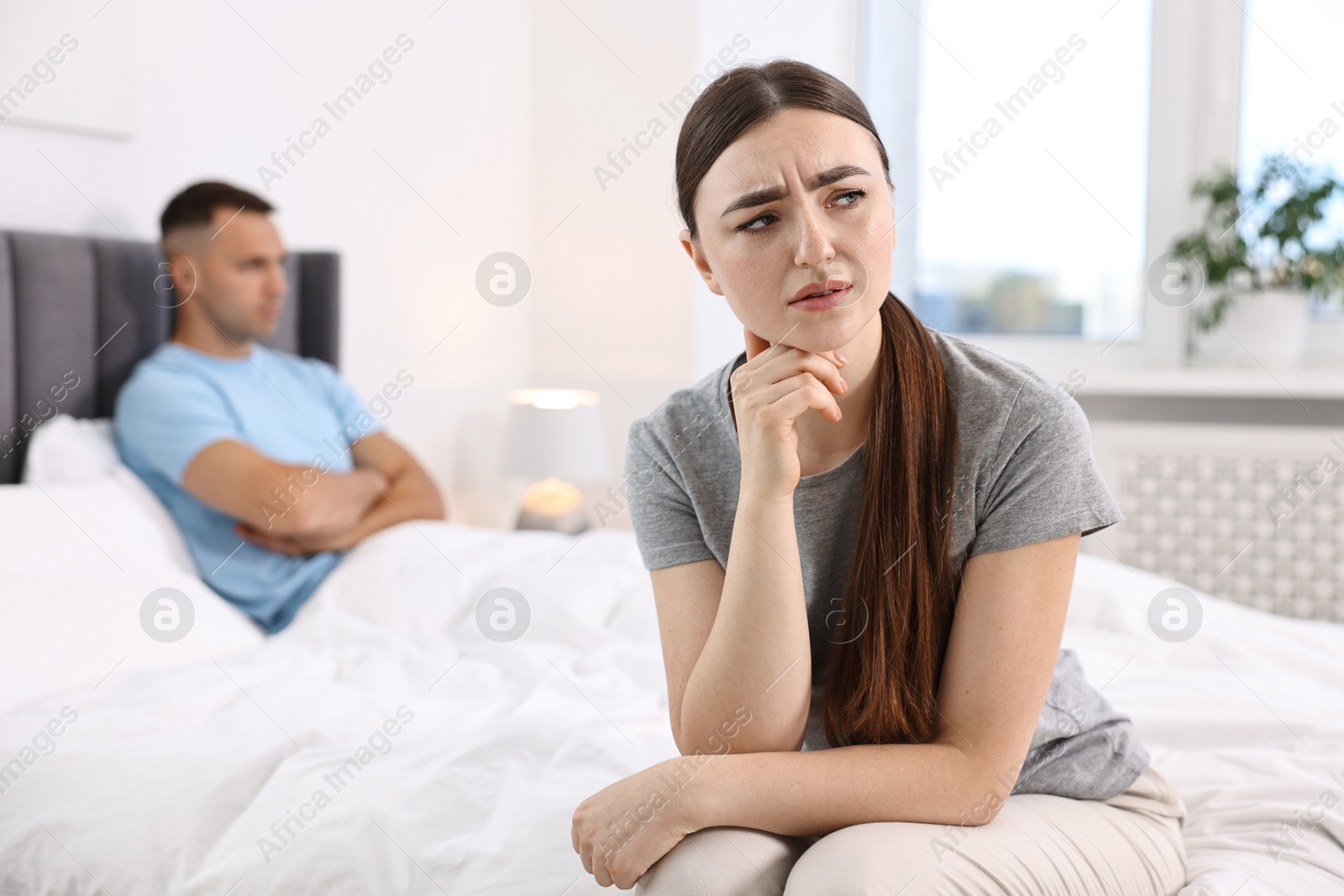 Photo of Offended couple ignoring each other in bedroom, selective focus