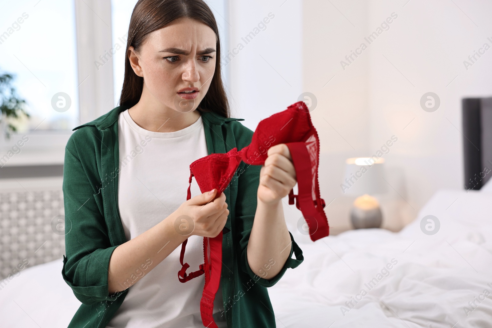 Photo of Surprised wife finding mistress bra in bedroom