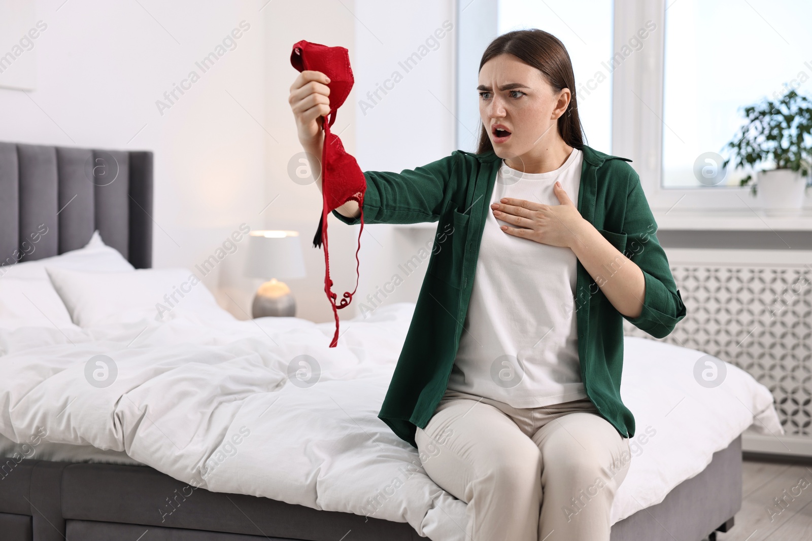 Photo of Surprised wife finding mistress bra in bedroom