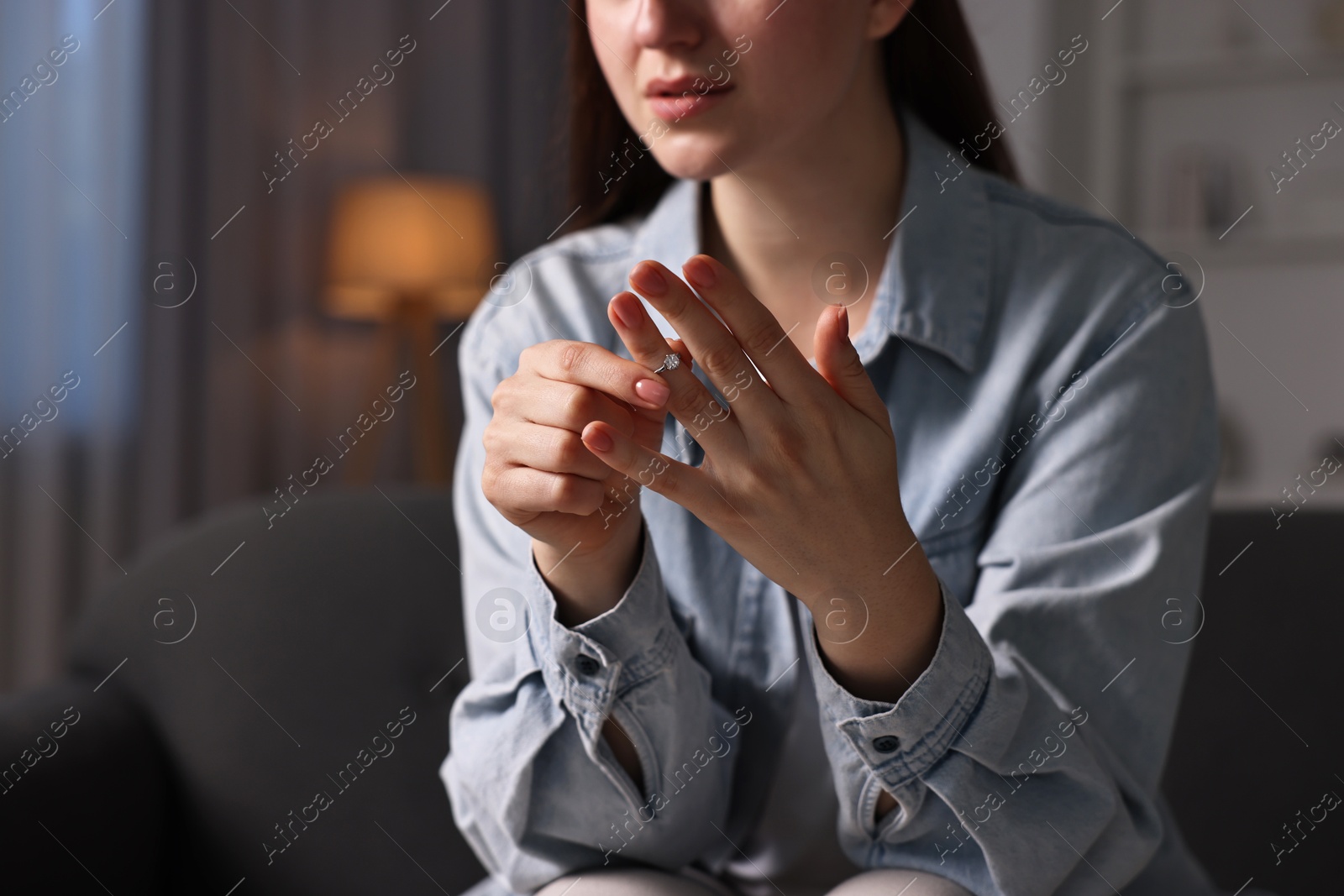 Photo of Woman taking off engagement ring at home, closeup