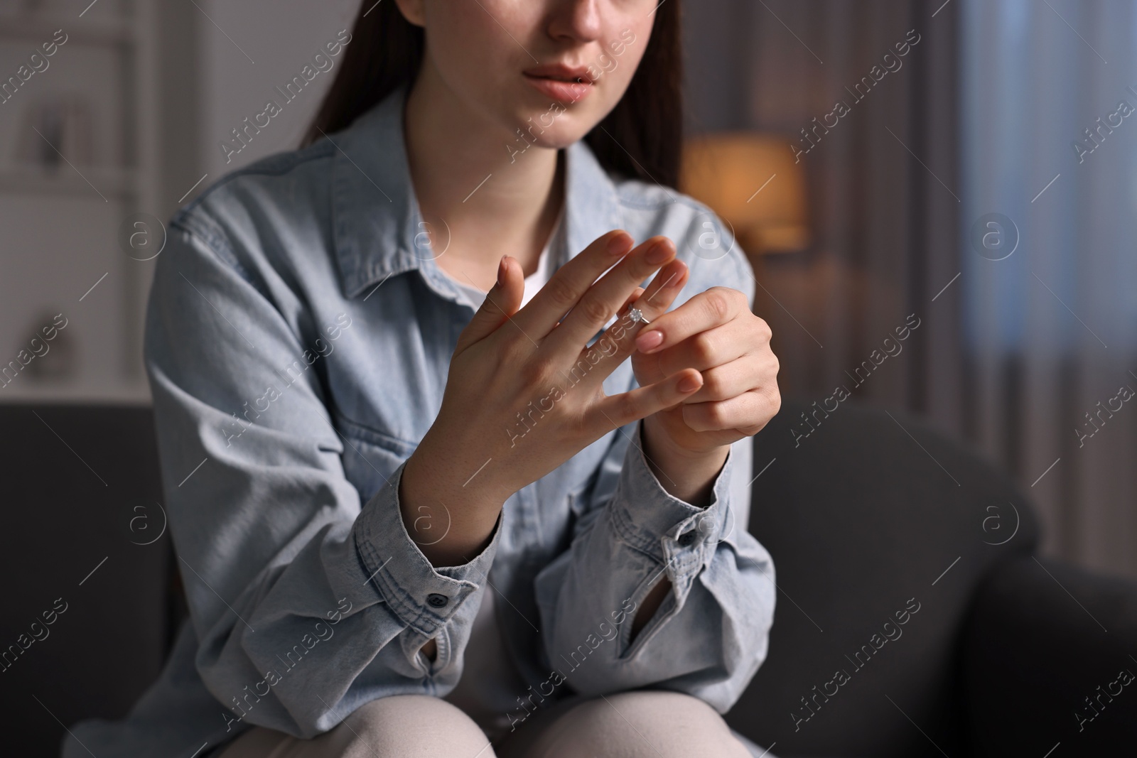 Photo of Woman taking off engagement ring at home, closeup