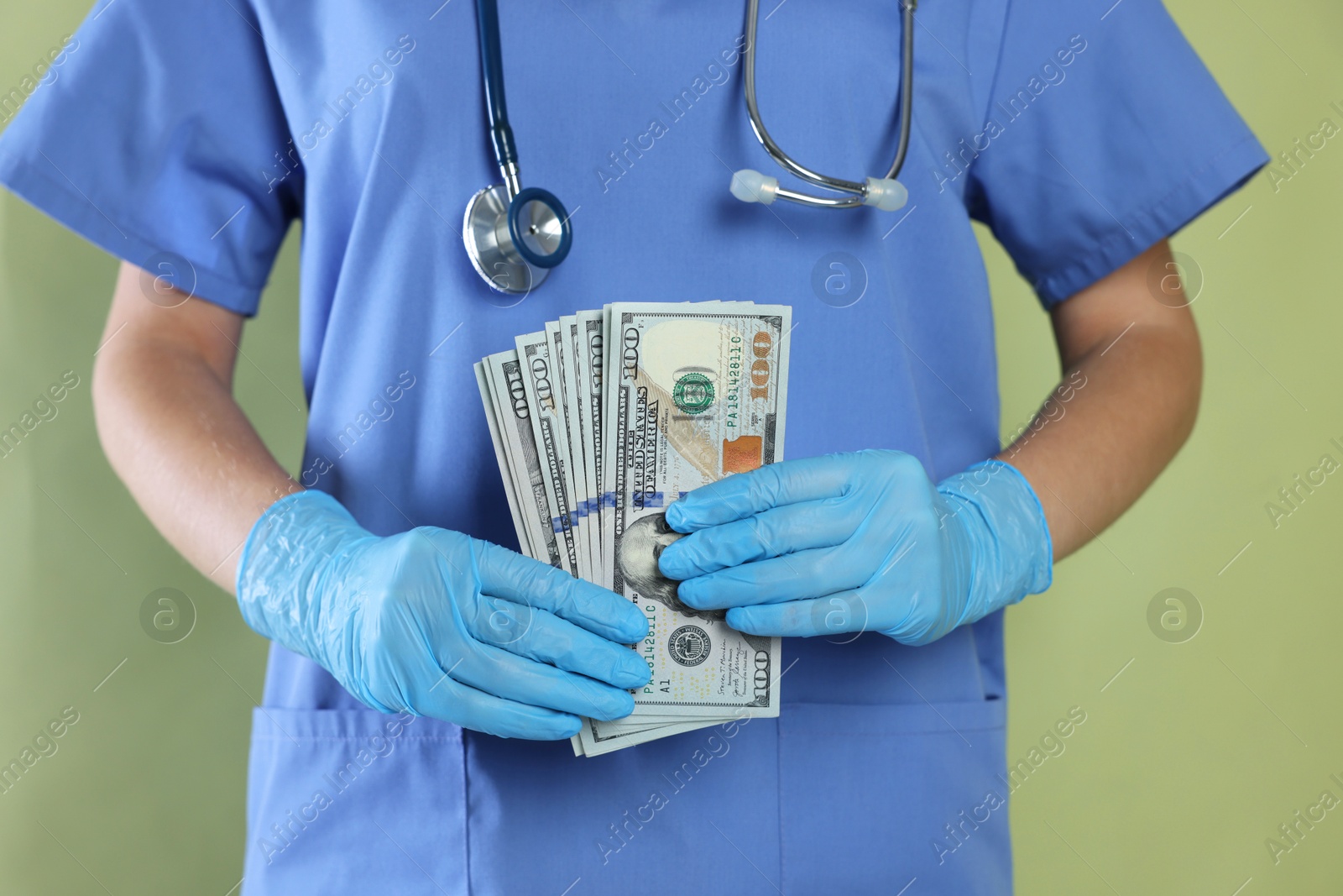 Photo of Corruption concept. Doctor with dollar banknotes on green background, closeup