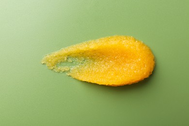 Photo of Smear of body scrub on green background, top view