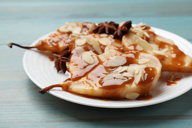 Photo of Delicious pears with caramel sauce, almond flakes and anise stars on light blue wooden table, closeup