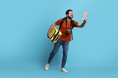 Photo of Traveller with passport, ticket and suitcase on light blue background