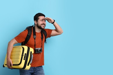 Photo of Traveller with suitcase and vintage camera on light blue background, space for text