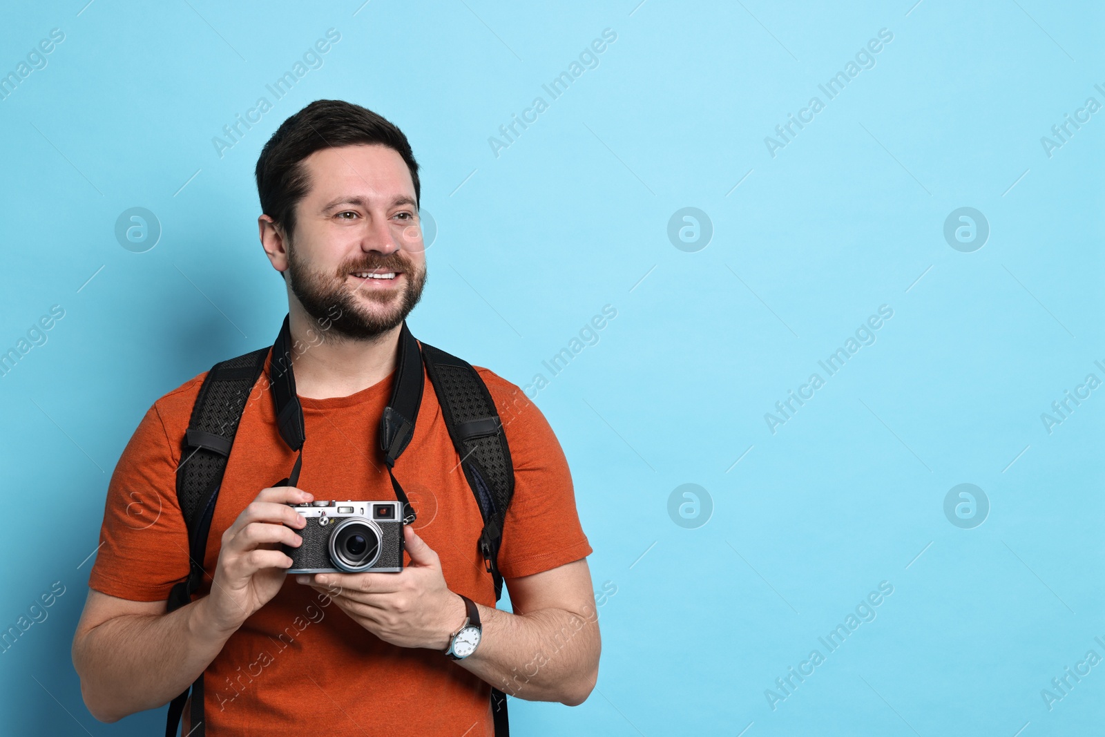 Photo of Traveller with vintage camera on light blue background, space for text