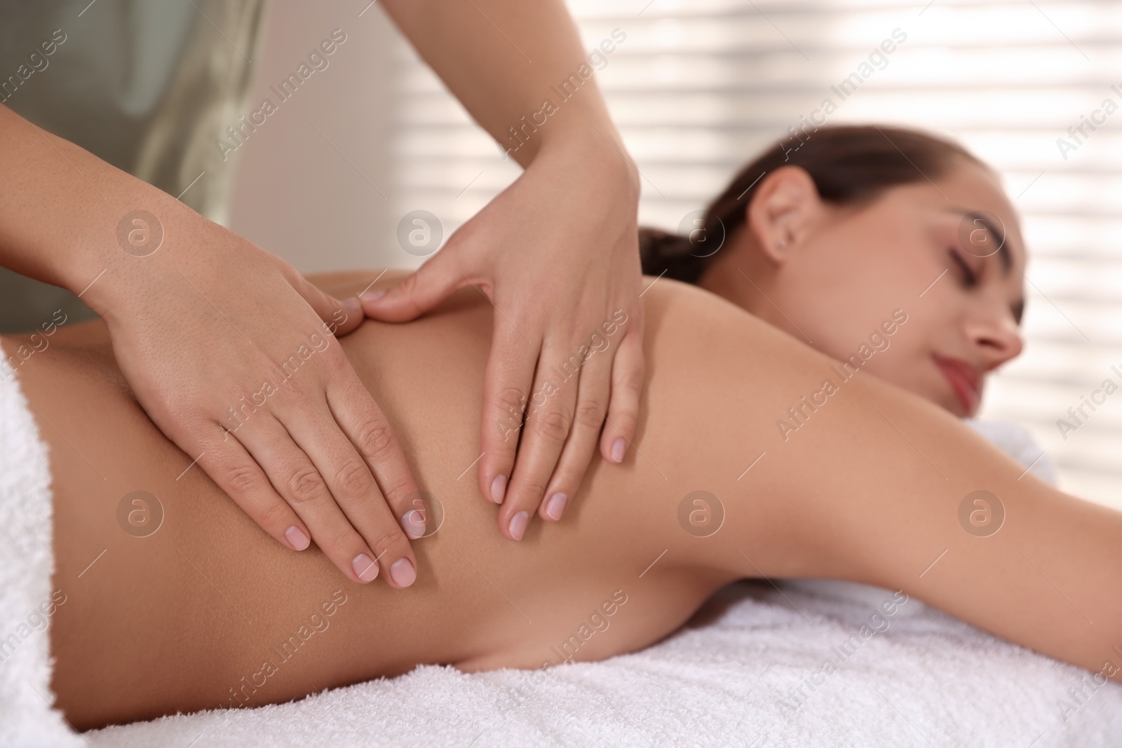 Photo of Young woman receiving massage in spa salon, selective focus