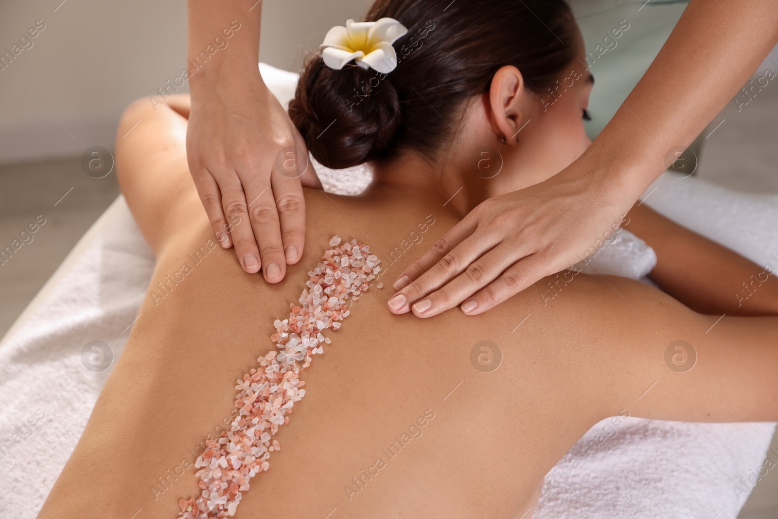 Photo of Woman receiving massage with sea salt in spa salon