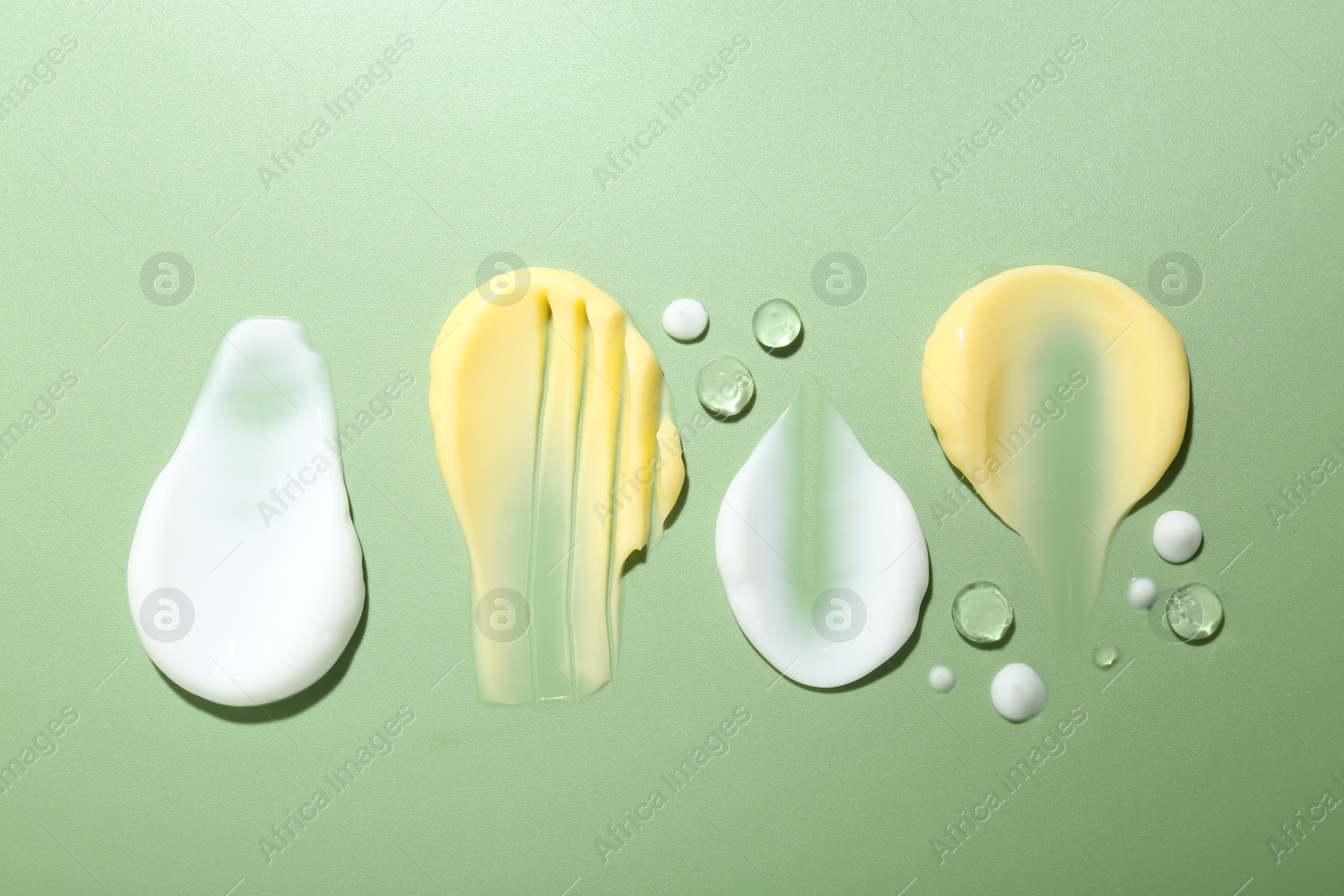 Photo of Cream and gel samples on light green background, flat lay