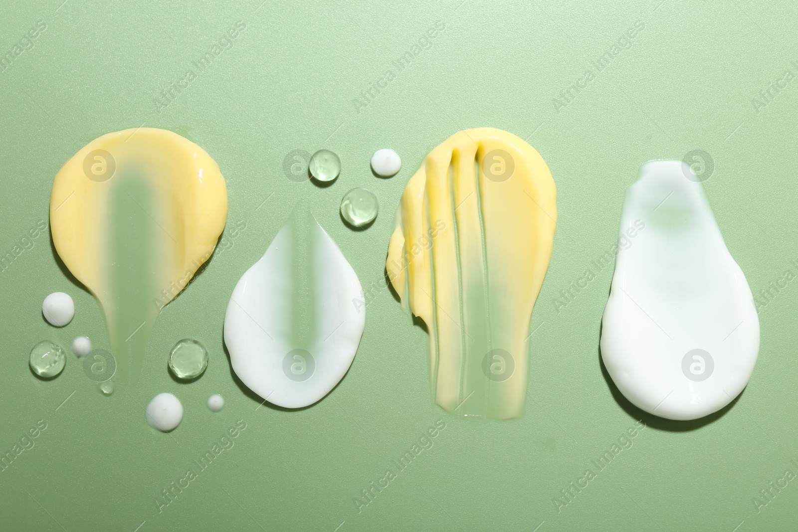 Photo of Cream and gel samples on light green background, flat lay