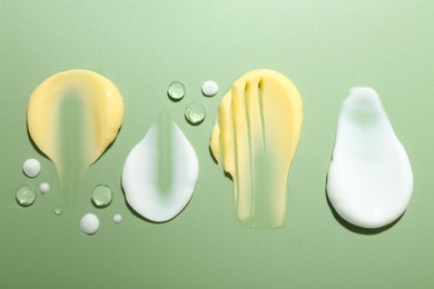 Photo of Cream and gel samples on light green background, flat lay