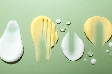 Photo of Cream and gel samples on light green background, flat lay