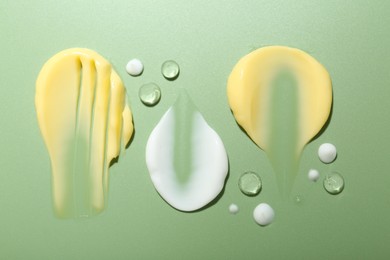 Photo of Cream and gel samples on light green background, flat lay