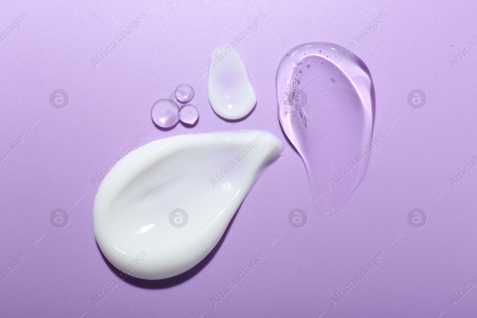 Photo of Cream and gel samples on violet background, flat lay