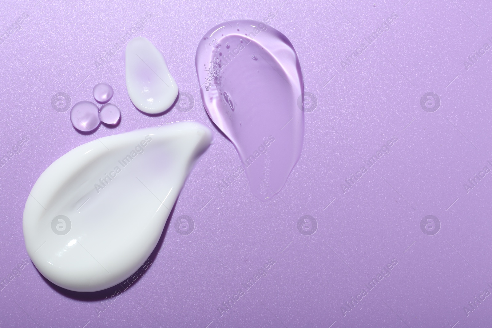 Photo of Cream and gel samples on violet background, flat lay. Space for text