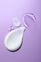 Photo of Cream and gel samples on violet background, flat lay