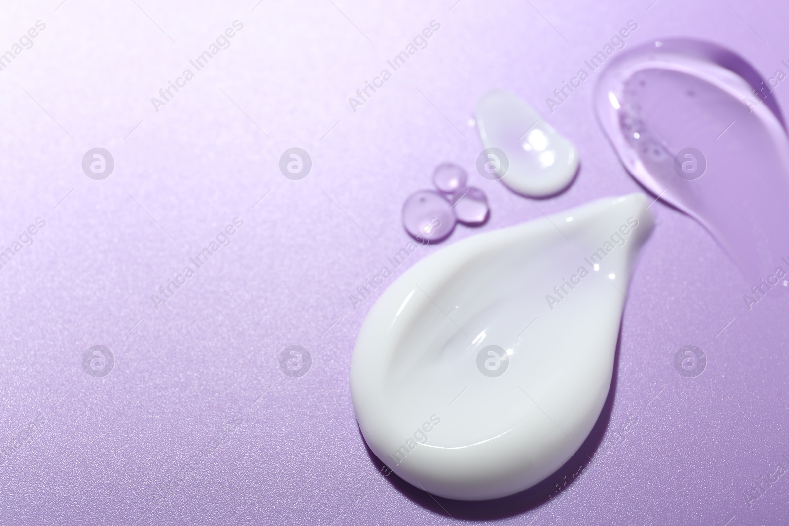 Photo of Cream and gel samples on violet background, closeup. Space for text