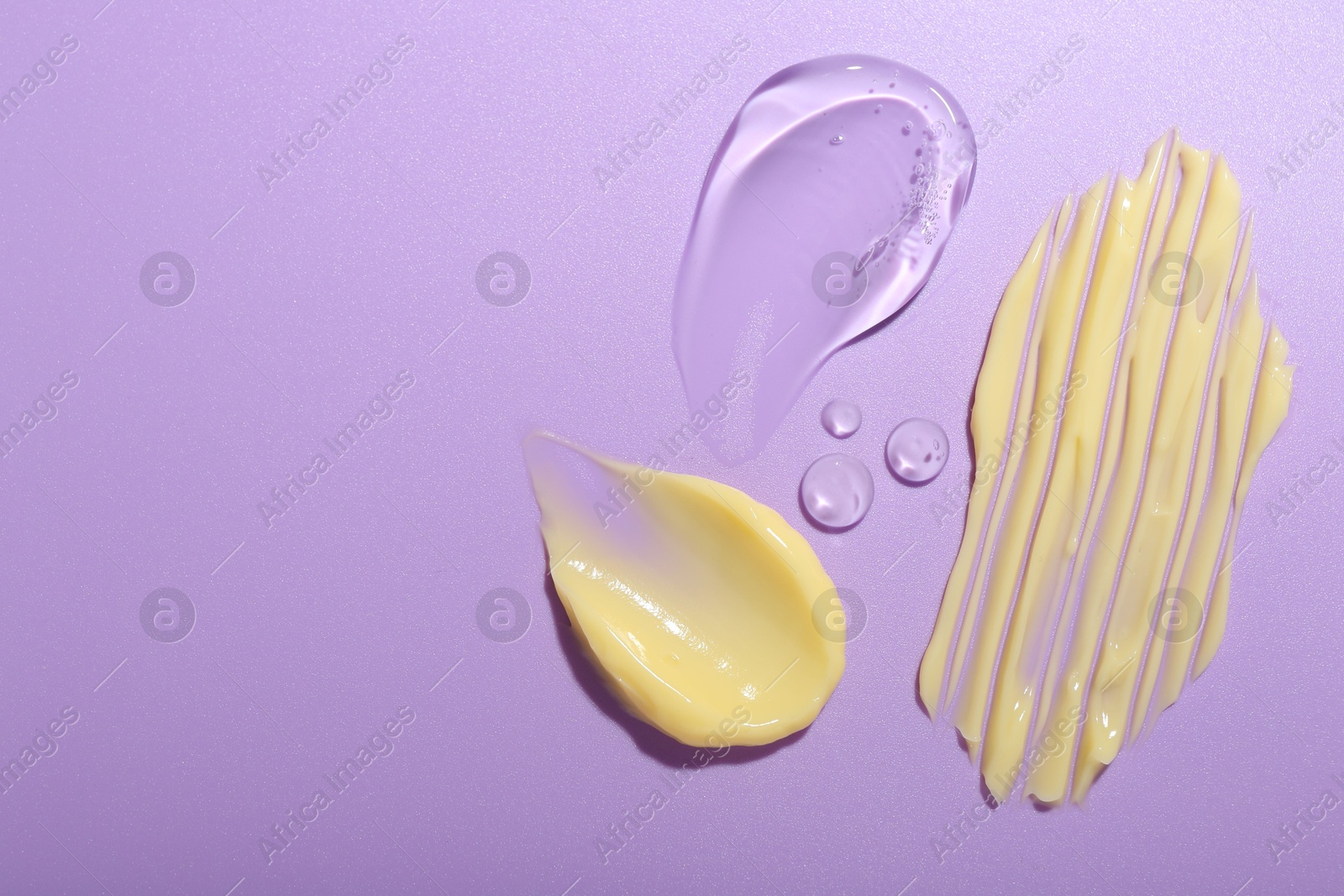 Photo of Cream and gel samples on violet background, flat lay. Space for text