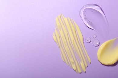 Photo of Cream and gel samples on violet background, flat lay. Space for text