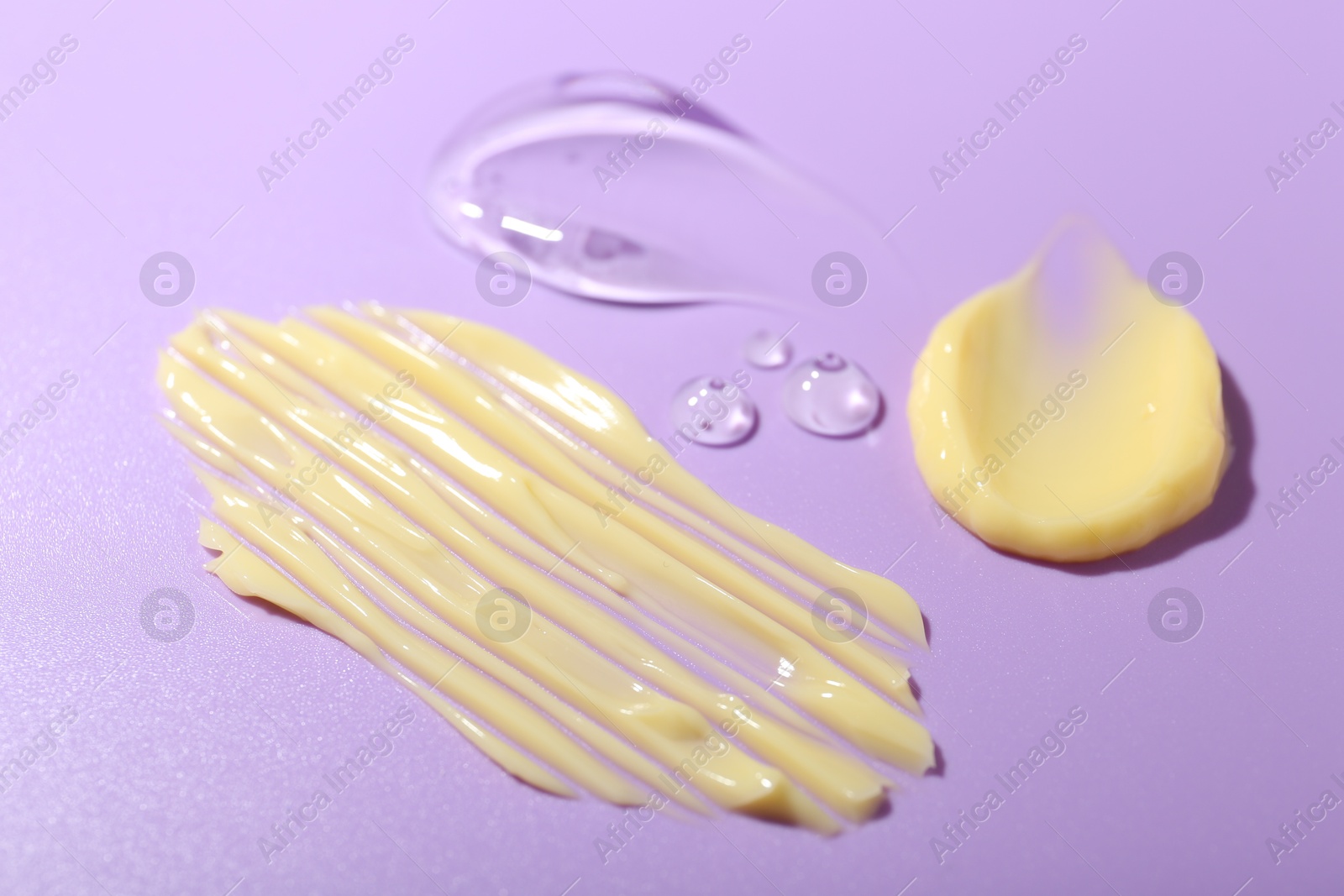 Photo of Cream and gel samples on violet background, closeup