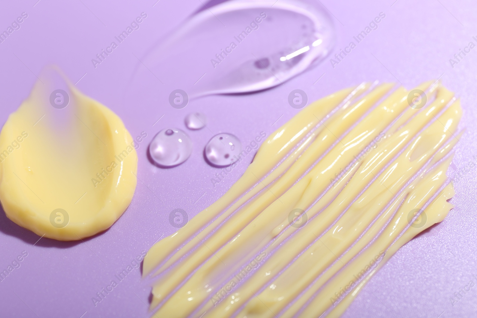 Photo of Cream and gel samples on violet background, closeup