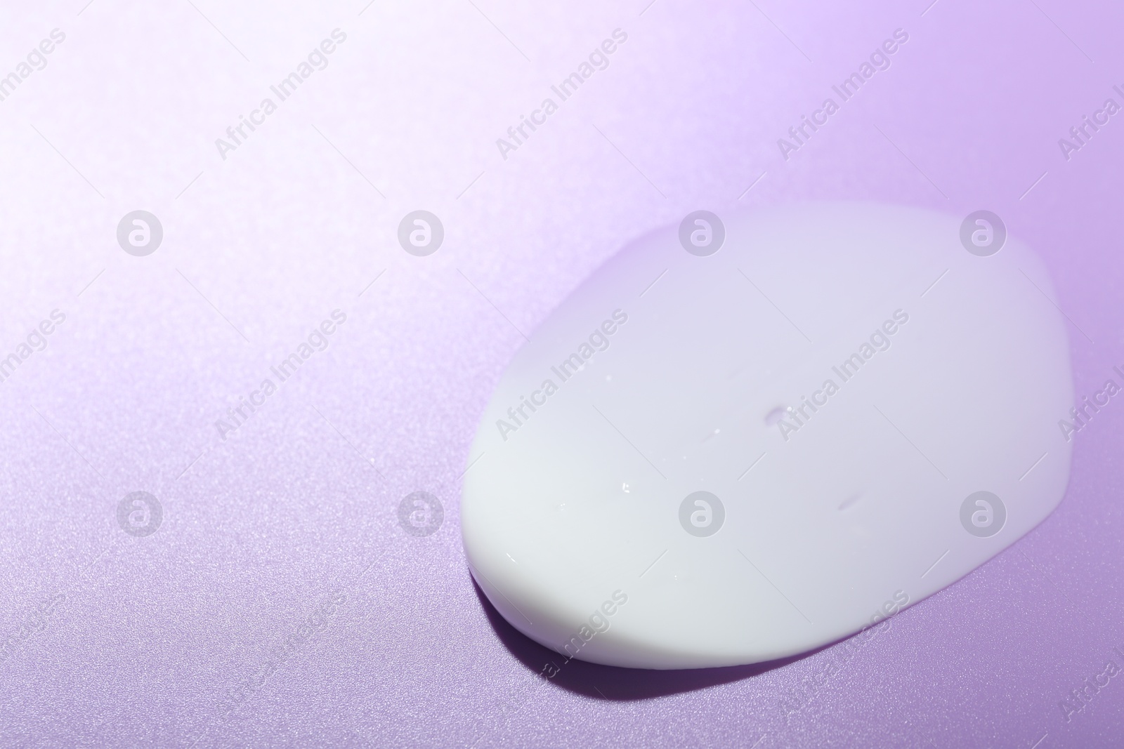 Photo of Cream sample on violet background, closeup. Space for text