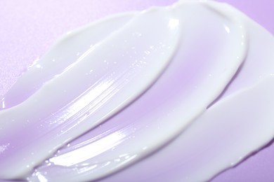 Photo of Cream sample on violet background, closeup view