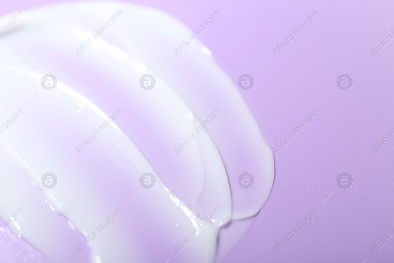 Photo of Cream sample on violet background, closeup. Space for text