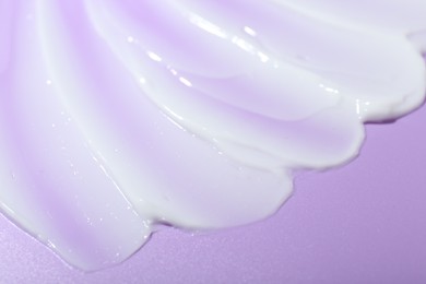 Photo of Cream sample on violet background, closeup view