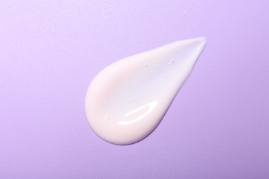 Cream sample on violet background, top view