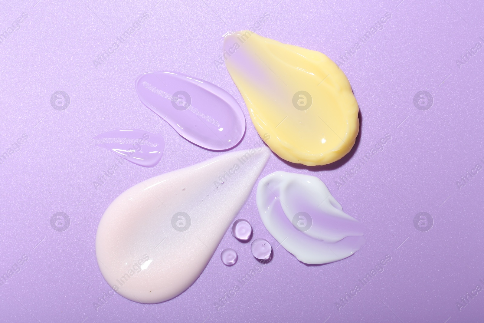 Photo of Cream and gel samples on violet background, top view