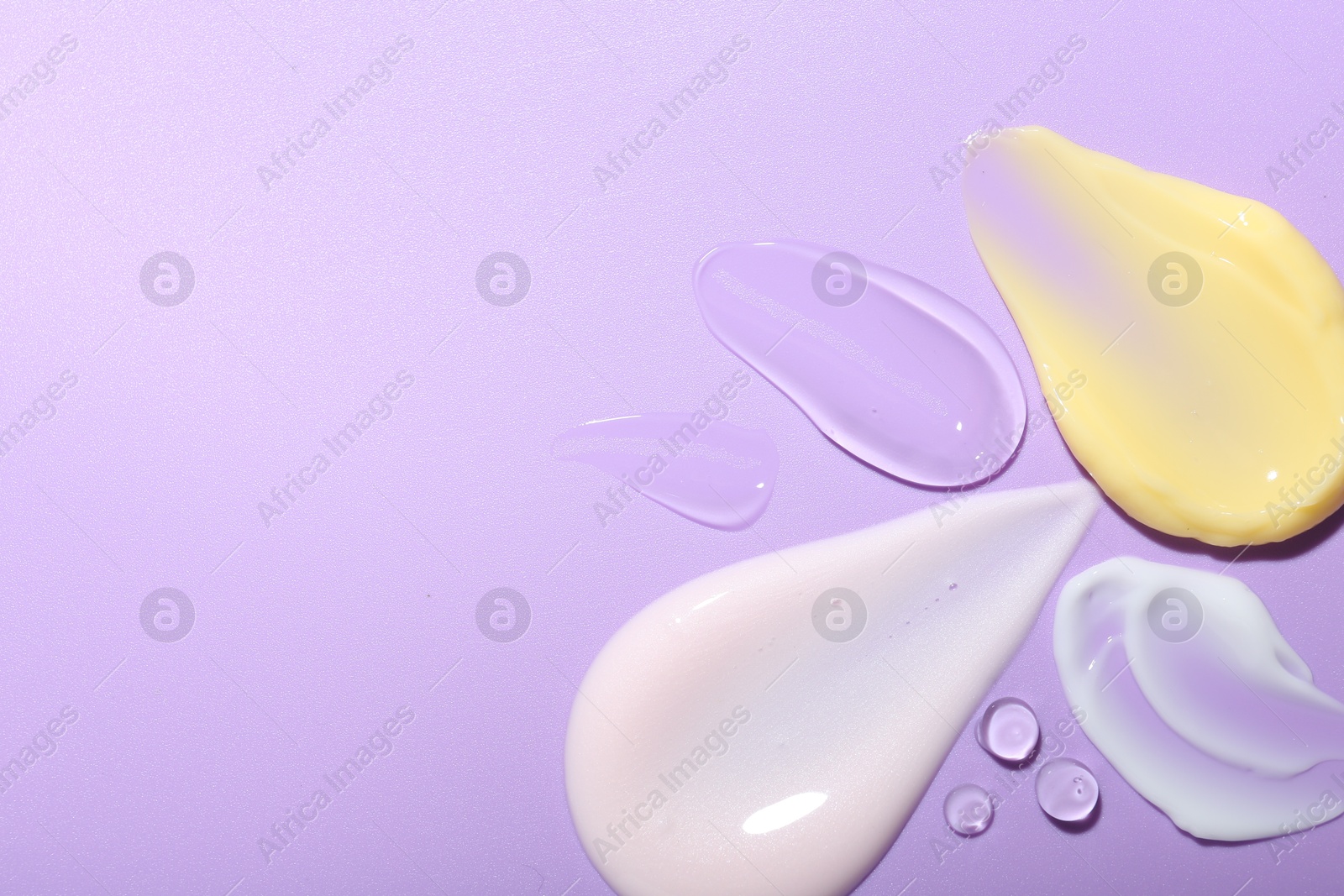 Photo of Cream and gel samples on violet background, top view. Space for text