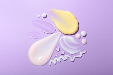 Photo of Cream and gel samples on violet background, top view