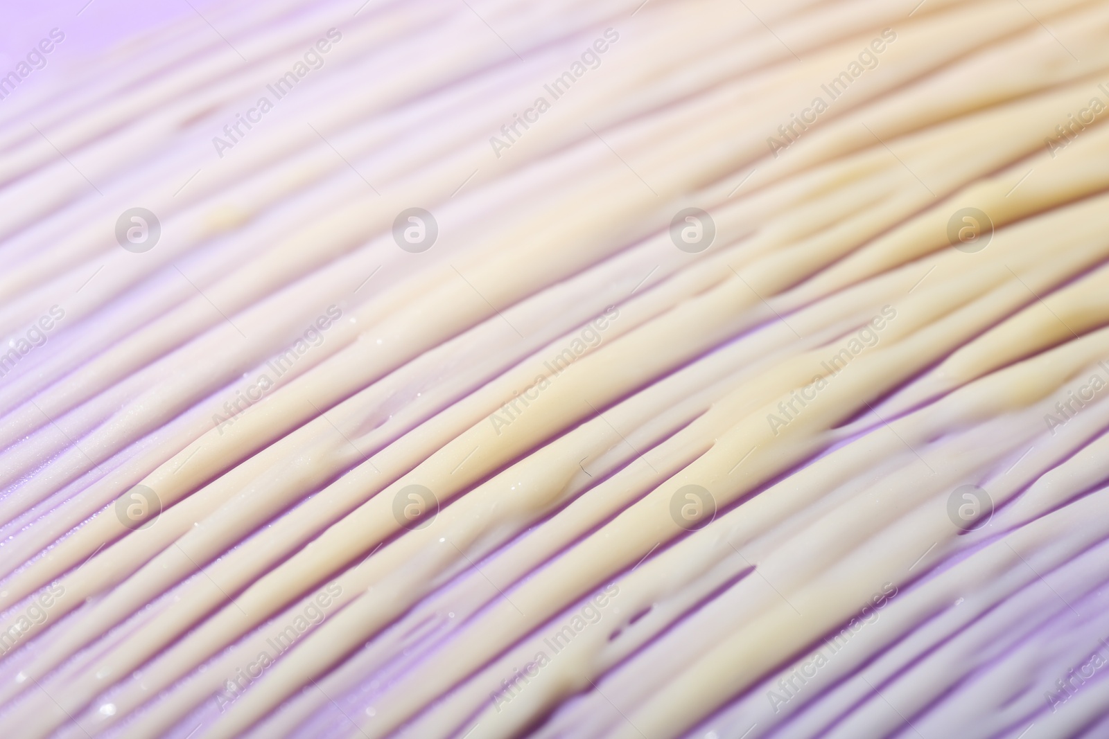 Photo of Cream sample on violet background, closeup view